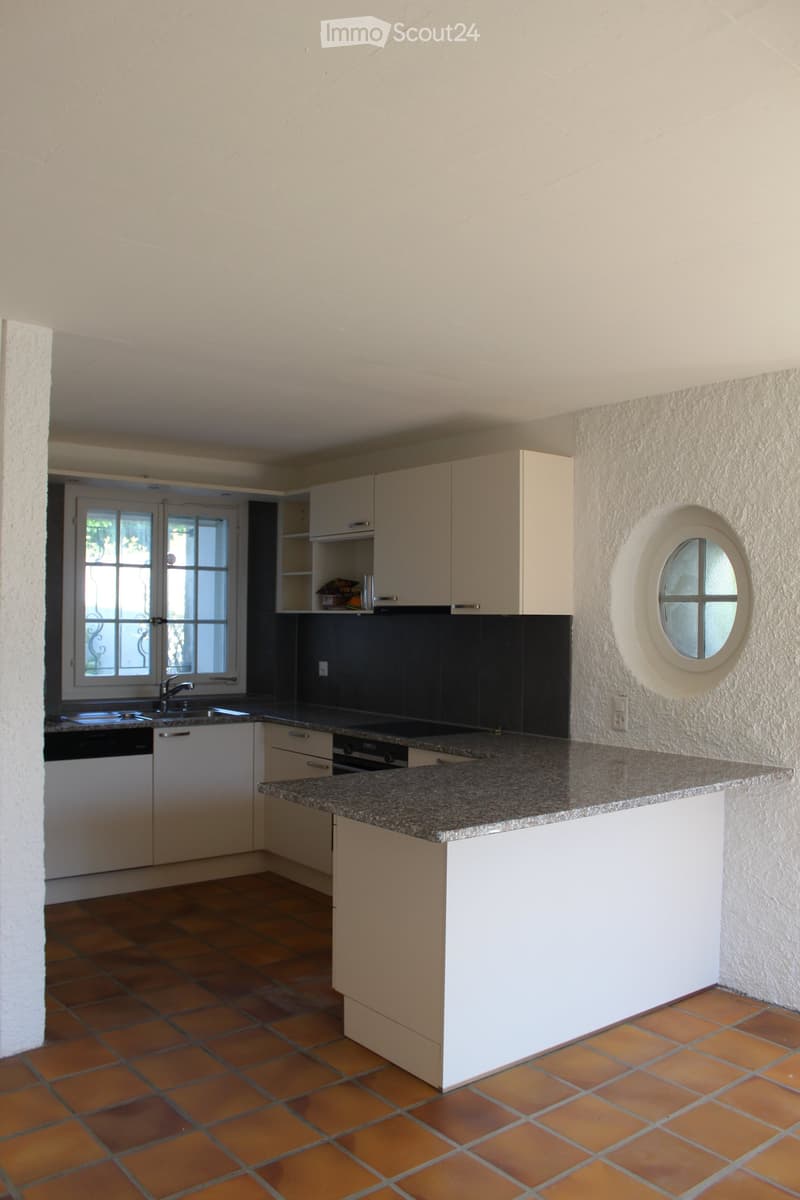 modern kitchen with white cabinets, granite countertop, round window, tiled floor