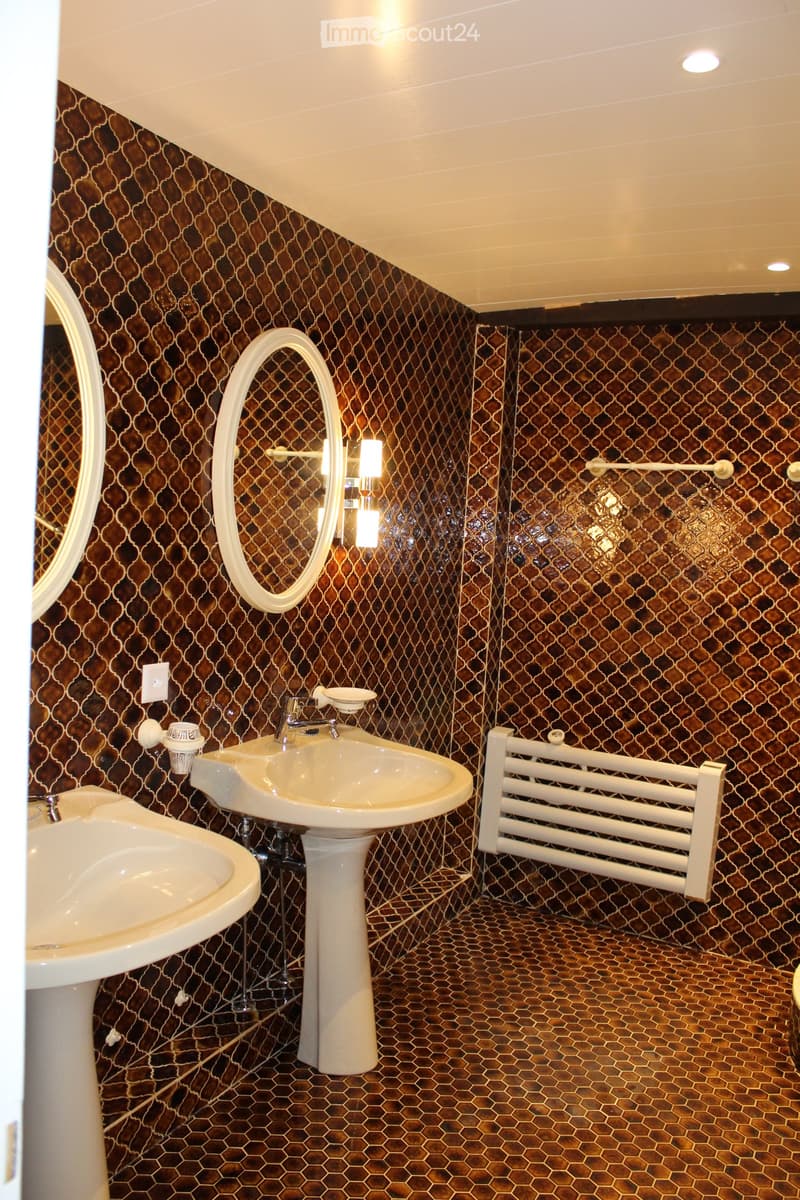 Bathroom with two sinks, two mirrors, and tiled walls and floor.