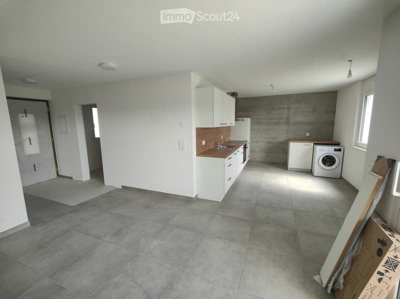 Open kitchen with modern appliances, white cabinets, tiled floor, and a washing machine