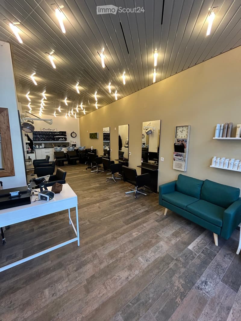 A salon with wooden floors, a green couch, mirrors, and various salon equipment.