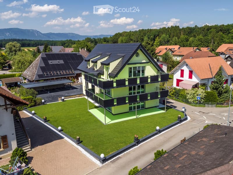House. Modern house with a green lawn, solar panels on the roof, and a balcony on the second floor.