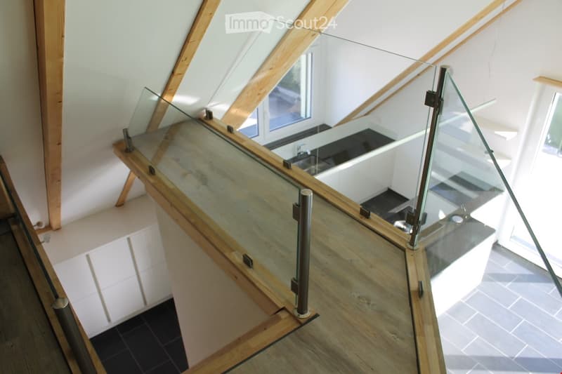 Furnished Room. A room with a wooden floor, glass railing, and a sink with a faucet. The room has a white wall and a wooden beam.