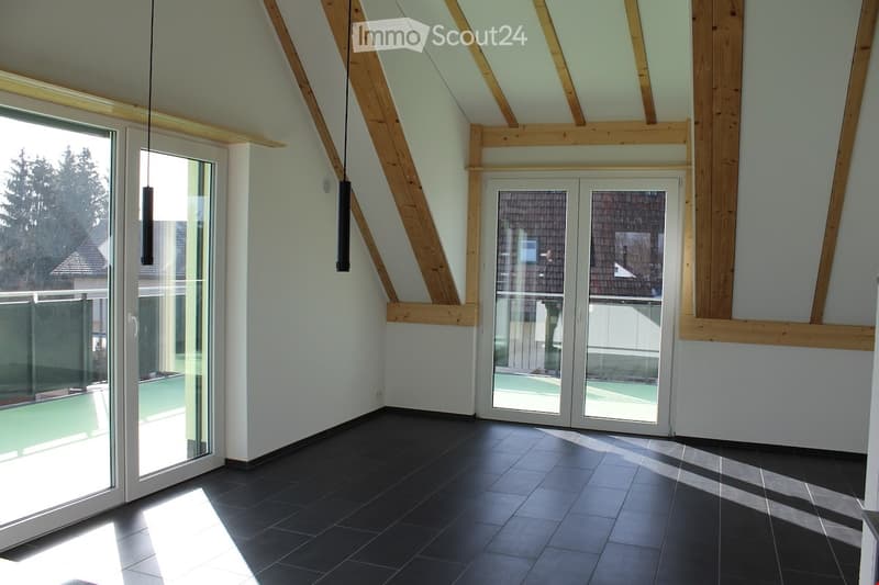 Unfurnished Room. Empty room with white walls, black tiled floor, wooden beams, and glass doors leading to a balcony.