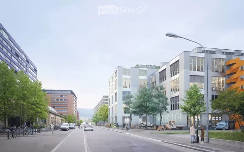 Urban street scene with modern buildings, streetlights, and trees. A few people are walking on the sidewalk, and some bicycles are parked. Vehicles are driving on the road.