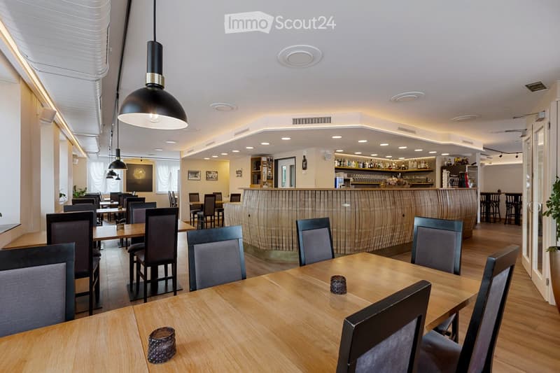 Dining area with long tables, bar counter, and comfortable chairs