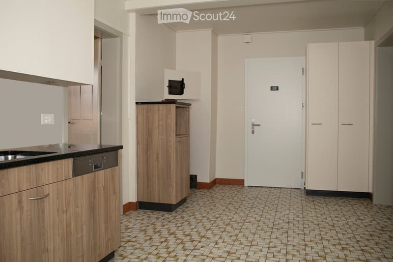 Modern kitchen with wooden cabinets, black countertop, stainless steel sink, and built-in microwave.