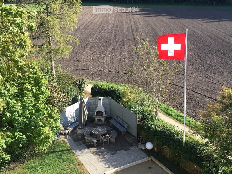 Outdoor area with a flag, a table, chairs, a bench, and an oven.