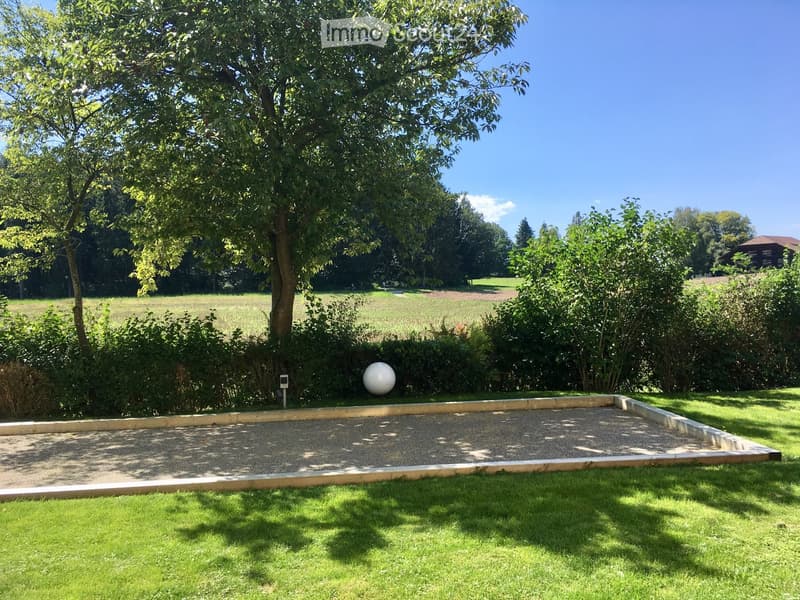 A rectangular bocce ball court surrounded by a hedge, with a white ball in the center.