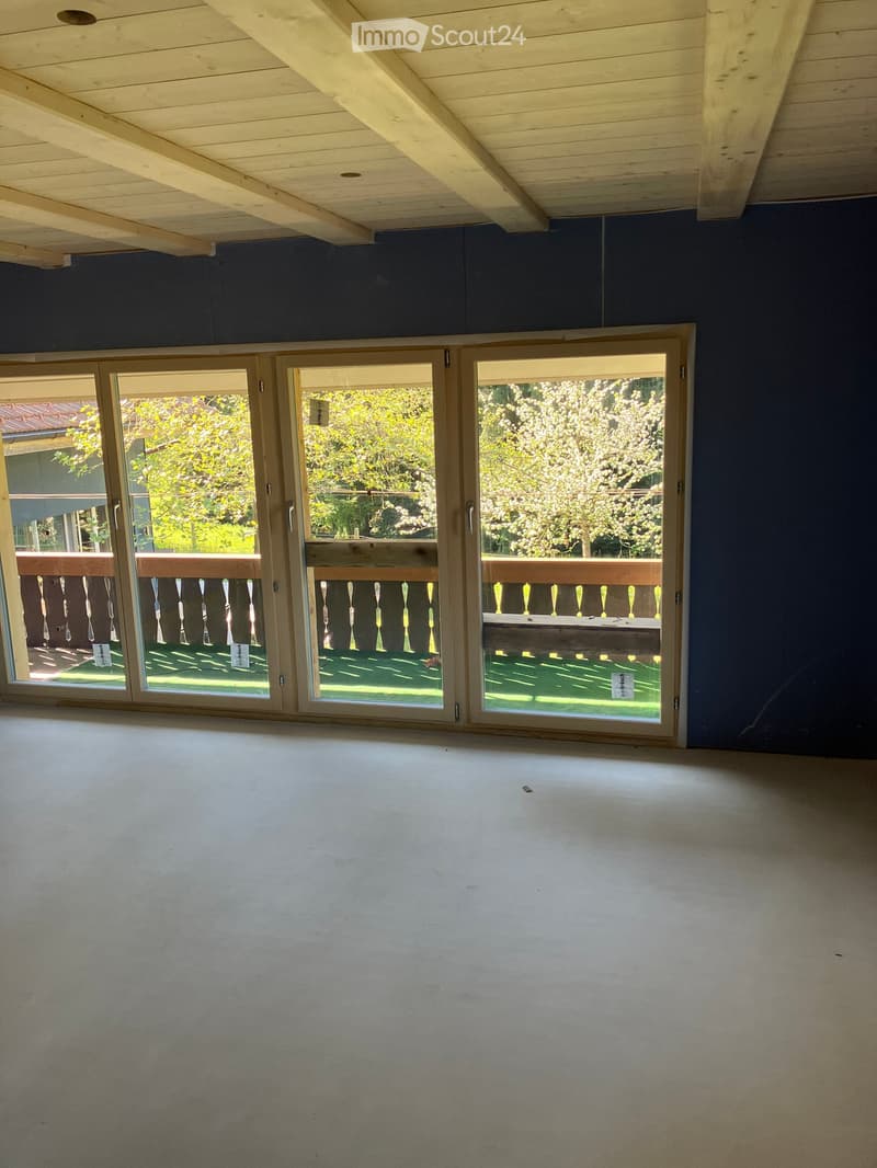 Unfurnished Room. Empty room with bare walls, wooden ceiling, and large glass doors leading to a balcony with a wooden railing.