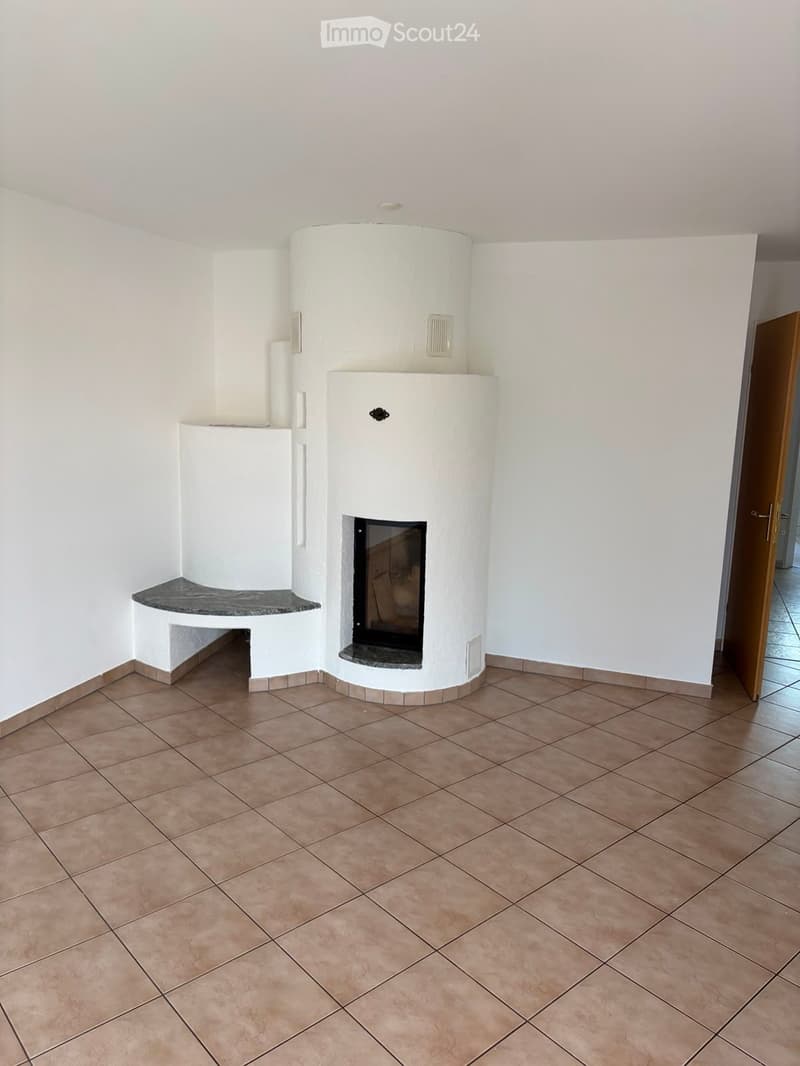Empty room with tiled floor, white walls, and a built-in fireplace with a stone surround and seating area.