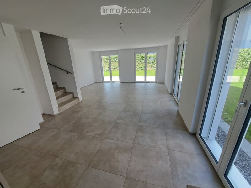 Empty room with tiled flooring, white walls, and large glass doors leading to a staircase and outdoor area.