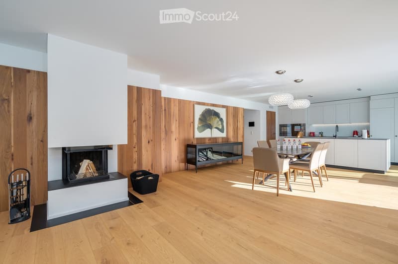 open floor plan, fireplace, wooden flooring, modern kitchen, dining area, wooden accent walls, pendant lights