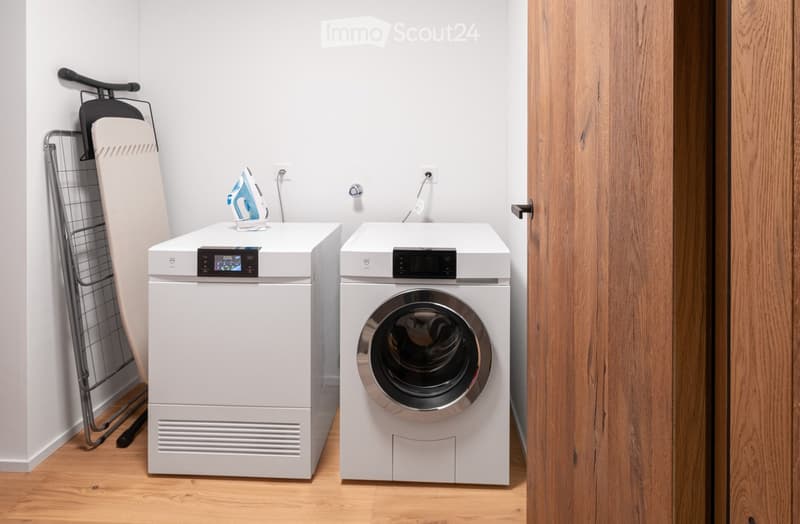 Laundry room with white appliances, hardwood flooring, and white walls