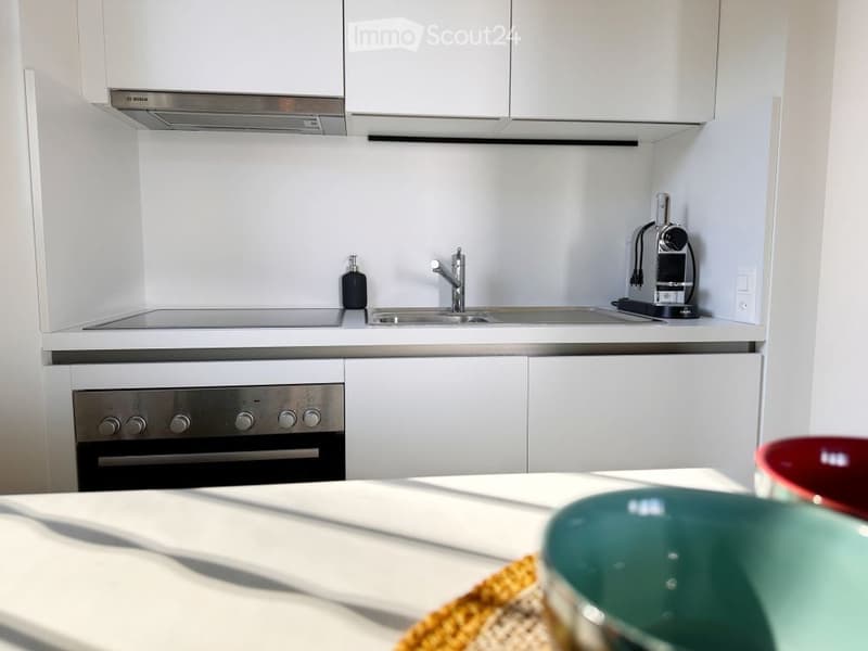 modern kitchen with white cabinets, stainless steel appliances, gas stove, sink, faucet, coffee machine, bowls on table