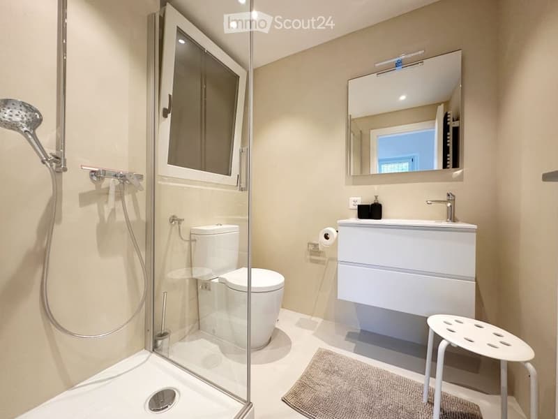 modern bathroom with shower, toilet, sink, mirror, and stool