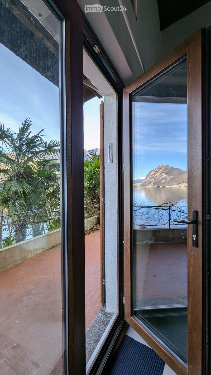 Open door leading to a balcony with a view of the lake and mountains