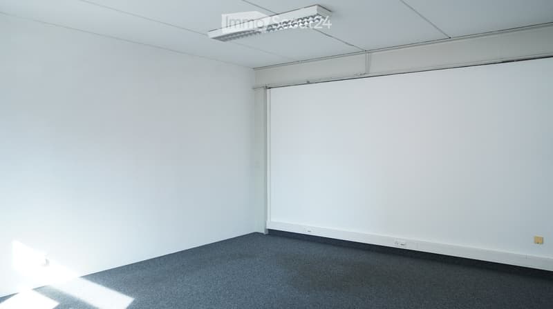 Completely empty room with white walls, ceiling, and gray carpet. There are two power outlets on the wall.