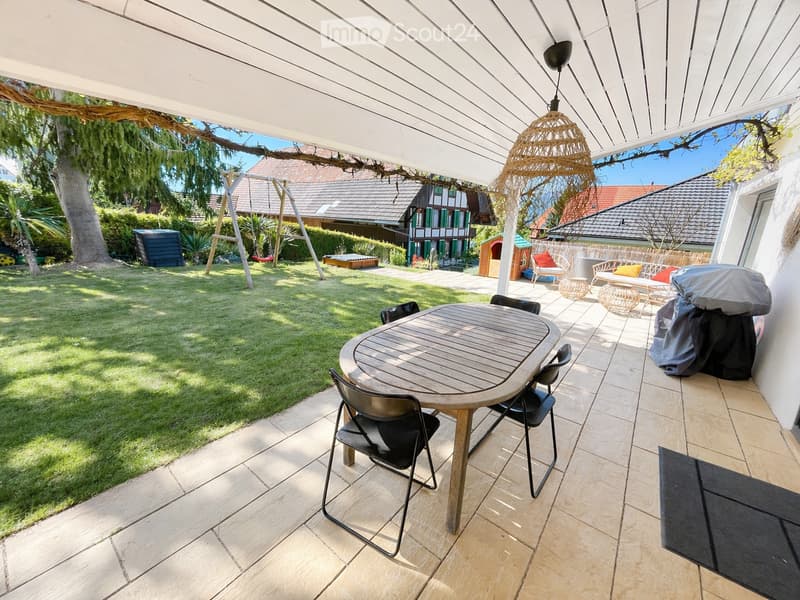wooden table and chairs, swing, green grass, trees, house in the background
