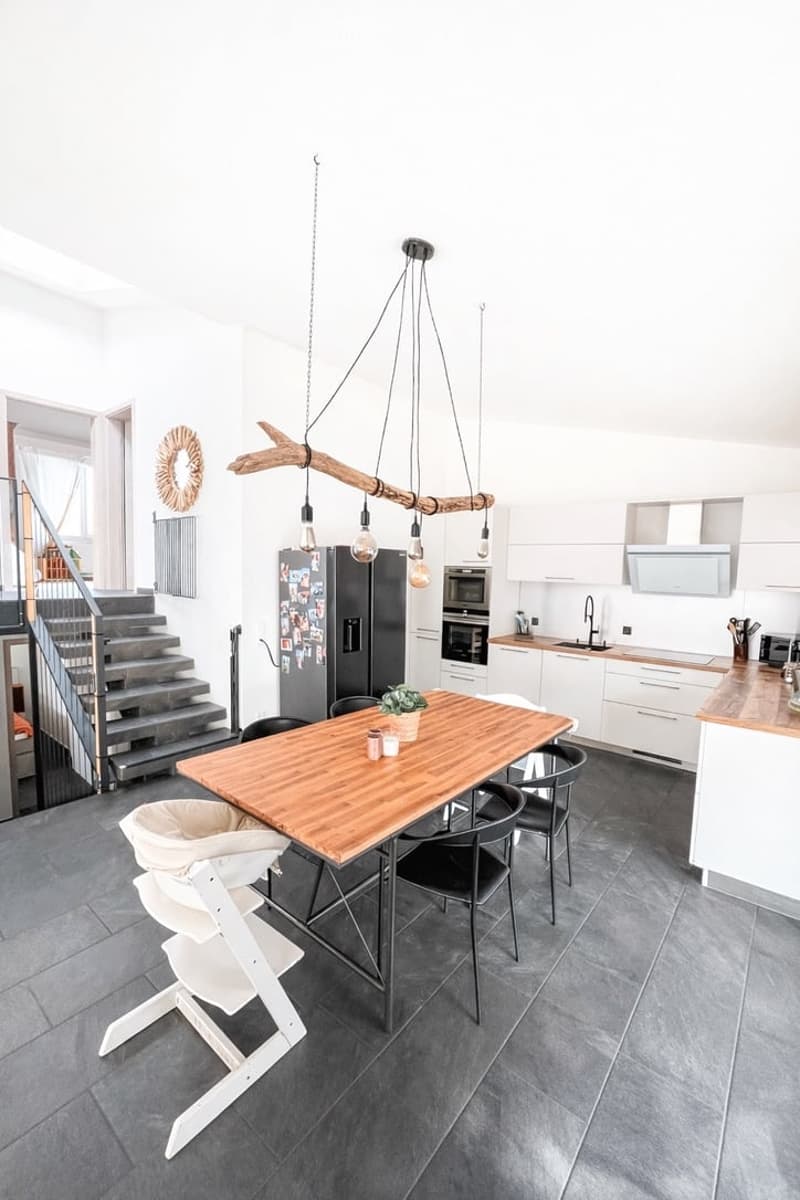 modern kitchen with dining area, wooden table, black chairs, white high chair, white cabinets, black fridge, wooden countertop, modern lighting