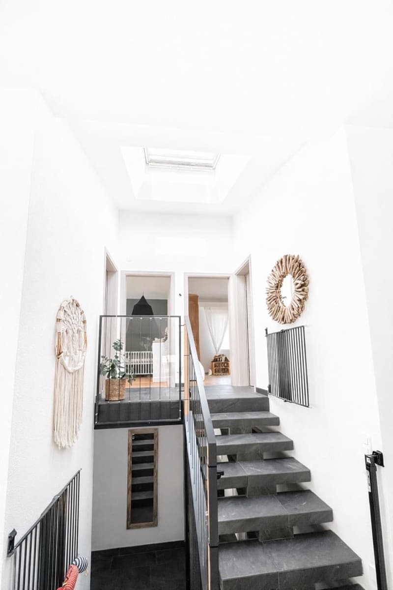 white walls, black tiled steps, black railings, skylight