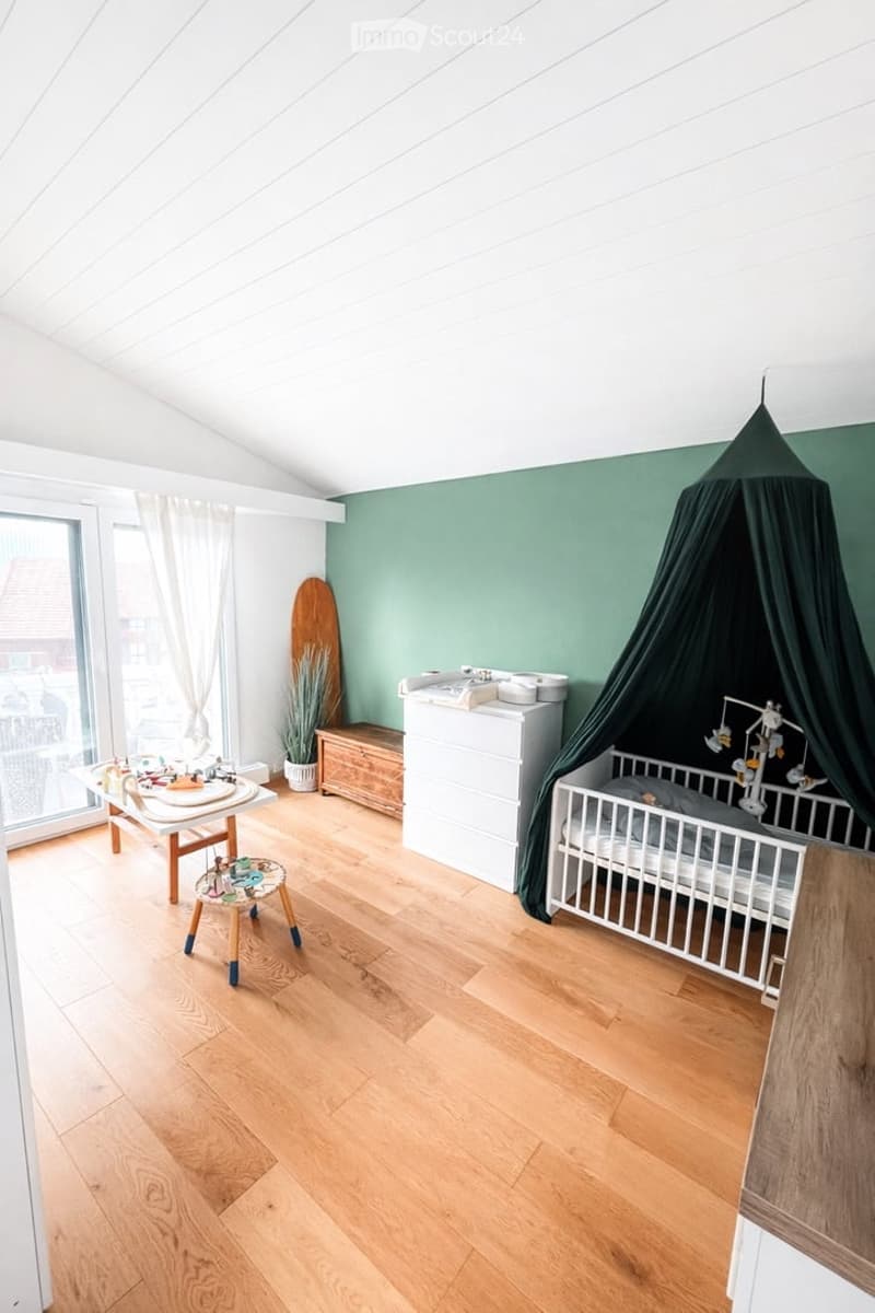 baby room with crib, canopy, wooden table, stool, wooden chest, white wardrobe, green wall, wooden floor, glass door, white curtains