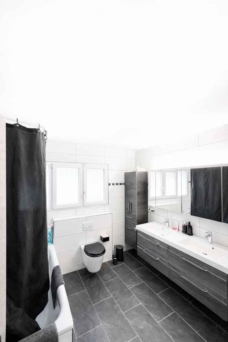 modern bathroom, white tiles, black tiles, bathtub, toilet, double sink, mirror, cabinets, power outlet