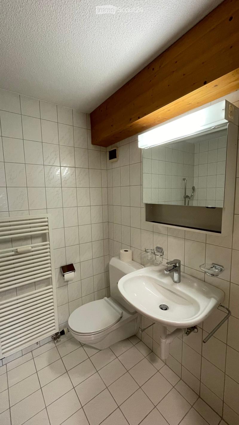 Toilet, white sink, white tiles, mirror, wooden beam
