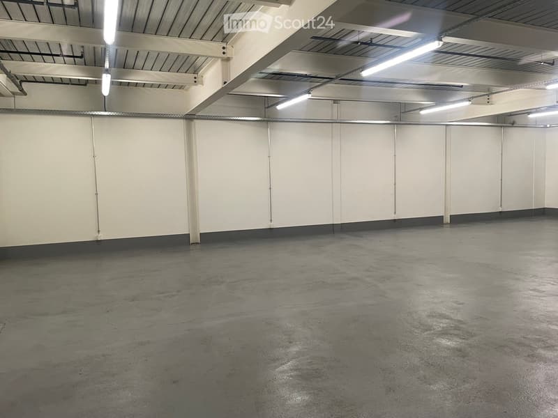 Unfurnished Room. Empty room with white walls, gray floor, and metal beams with lights on the ceiling.