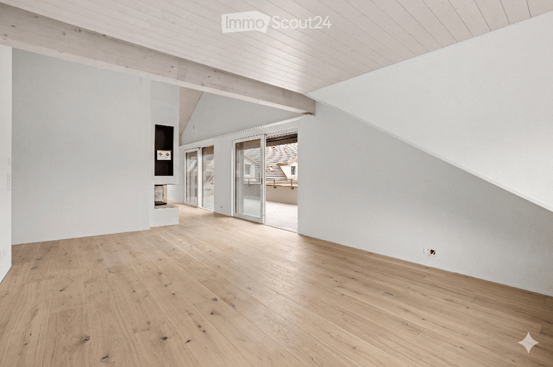 Empty room with light wooden flooring and white walls, featuring large glass doors leading to an outdoor area.