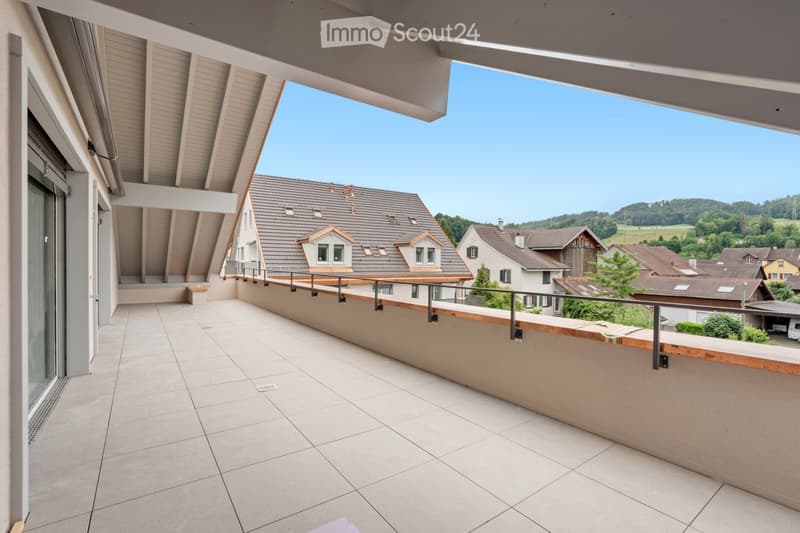 Balcony with tiled floor, wooden railing, and a view of a residential neighborhood with houses and greenery.