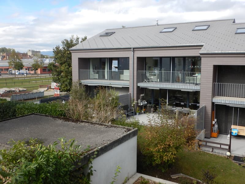 3 story house, gray exterior, multiple balconies, glass windows, garden area