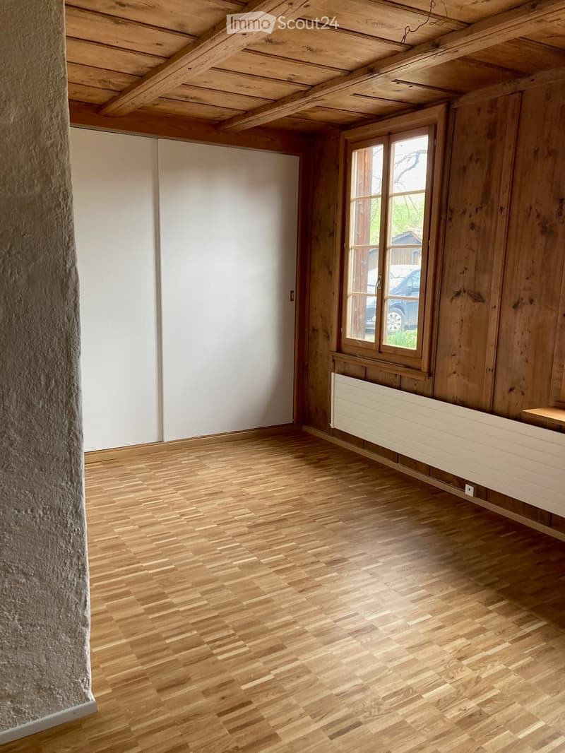 Unfurnished Room. Empty room with wooden floor, wooden walls, sliding doors, and a window with a view of a car.