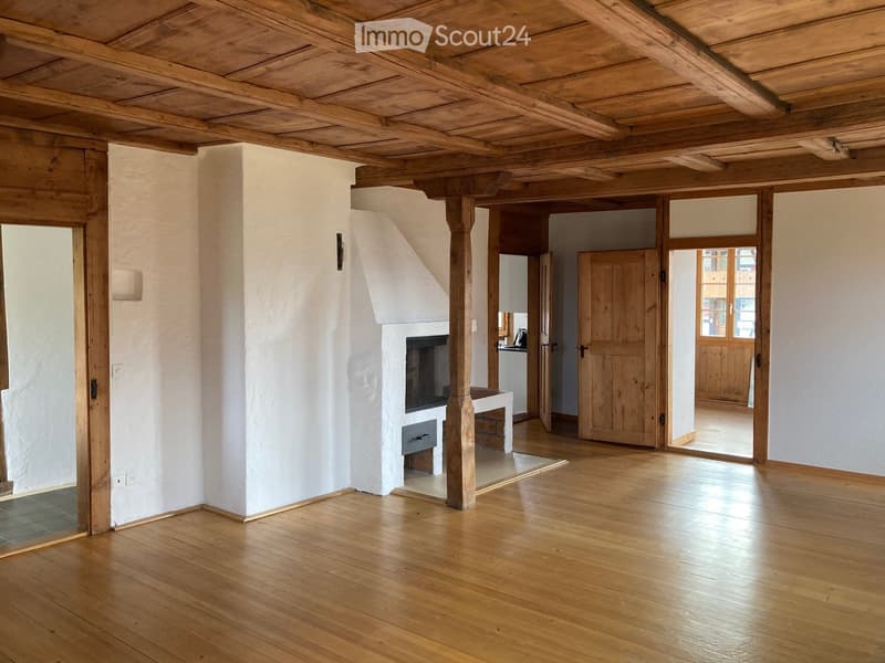Unfurnished Room. Empty room with wooden floors, white walls, wooden beams, fireplace, and open doors leading to other rooms.