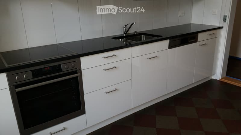 Modern kitchen with white cabinets, black countertops, stainless steel oven, and a sink with a faucet.