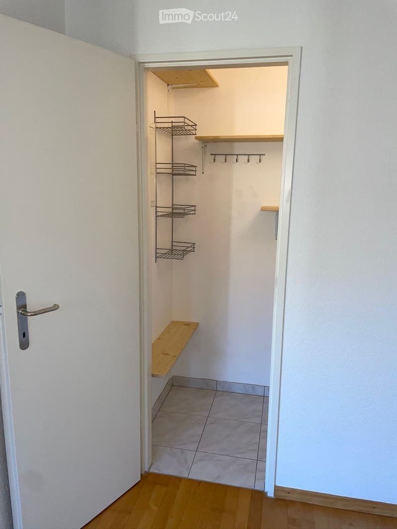 empty room with white walls, wooden floor, white tiled floor, wooden bench, metal shelves