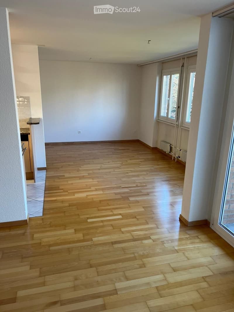 empty room, wooden floor, white walls, windows, kitchen area