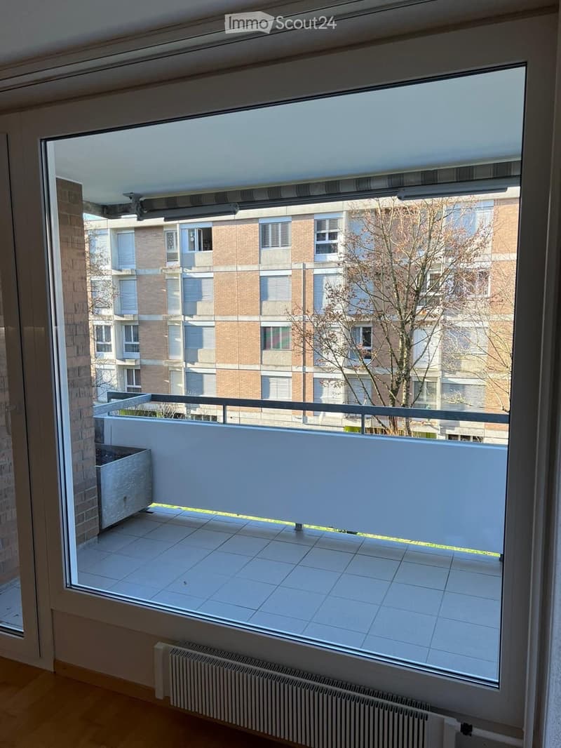 large window, balcony, tiled floor, radiator, view of a tree and building