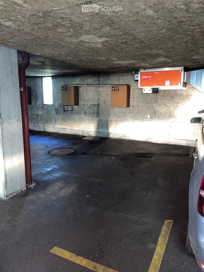 underground parking area, concrete walls, numbered parking spaces, a car parked