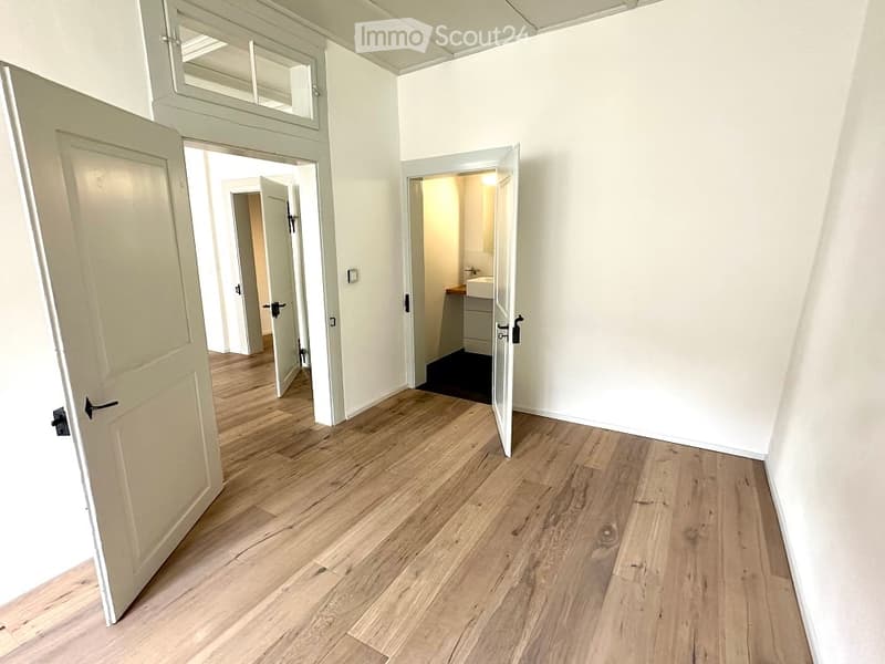 Empty room, wooden floor, white walls, open doors, bathroom sink, staircase