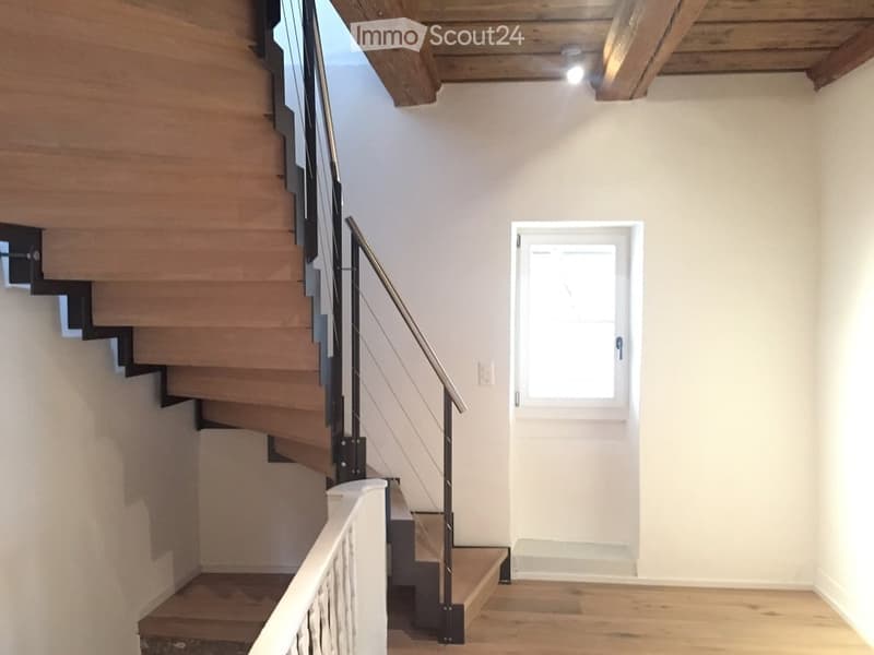wooden staircase with metal railing, wooden floor, white wall, small window