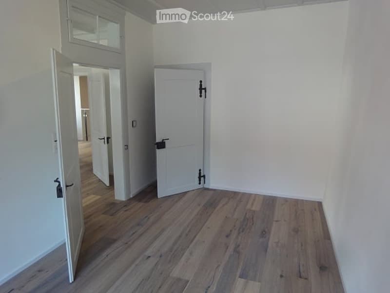 empty room with hardwood floors and white walls with 2 open doors
