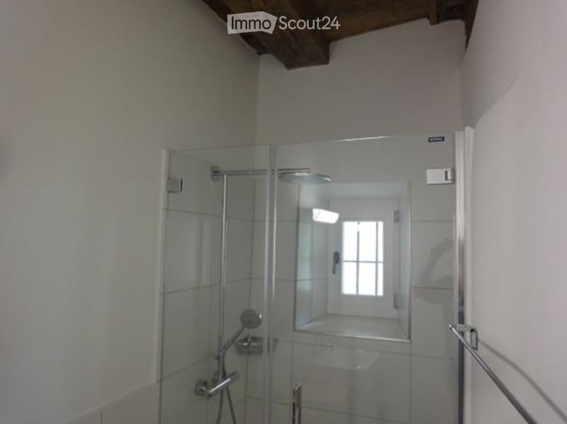Bathroom with glass shower stall, tiled walls, toilet bowl, a small window