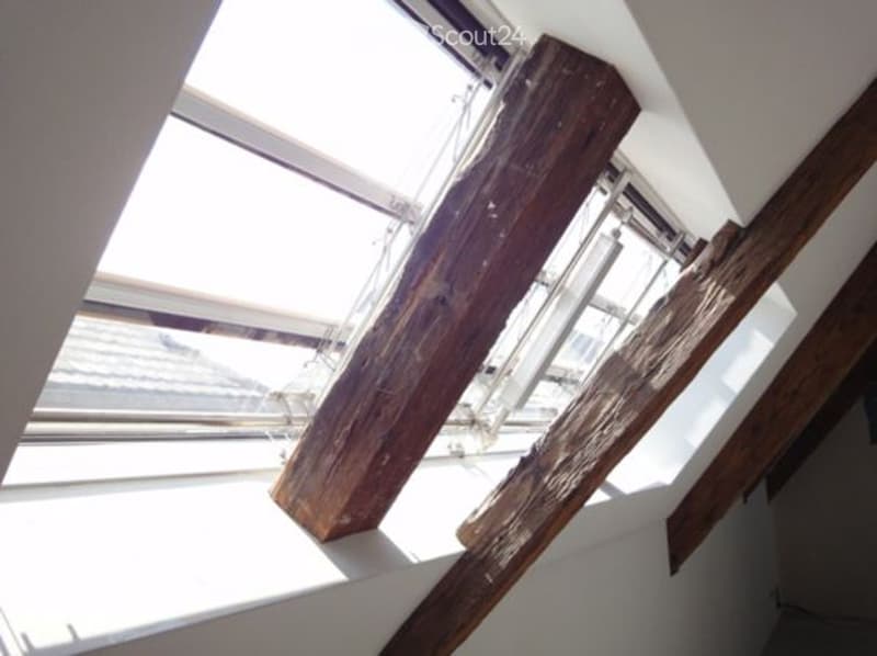 attic room with wooden beams and skylights