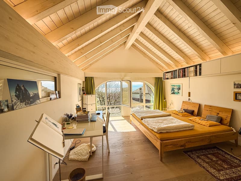 wooden ceiling, wooden floor, desk, two beds, bookshelves, picture frames, rug, window with curtains