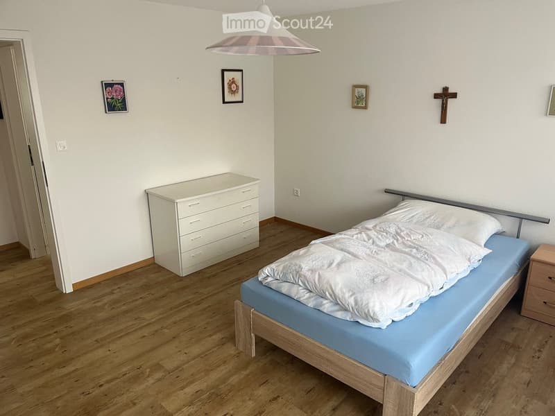 Bedroom. Bedroom with wooden flooring, a single bed with white bedding, a white dresser, a nightstand, and framed pictures on the wall.