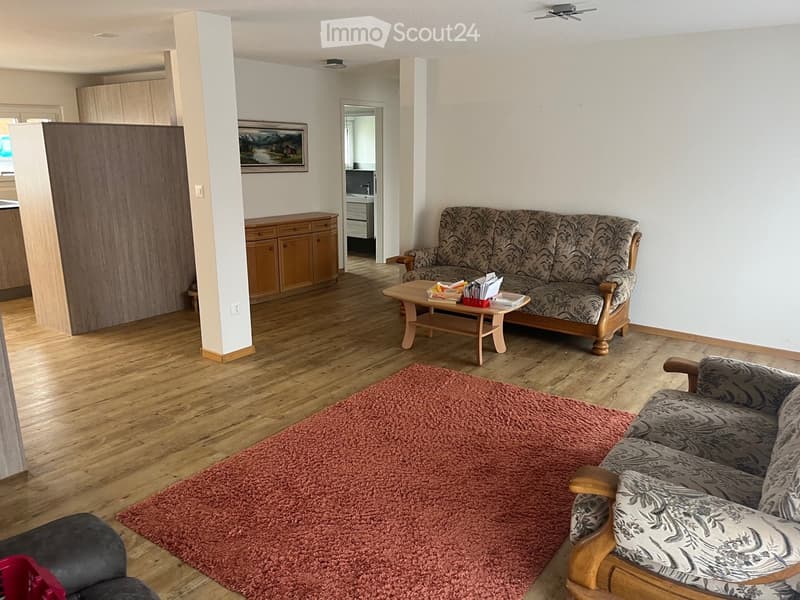 Living Room. Living room with wooden flooring, a patterned sofa, armchair, coffee table, and a red shag rug.