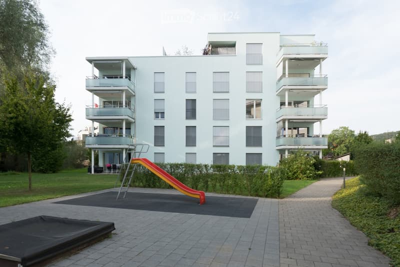 4 story building, balcony on each floor, red slide in front of the building
