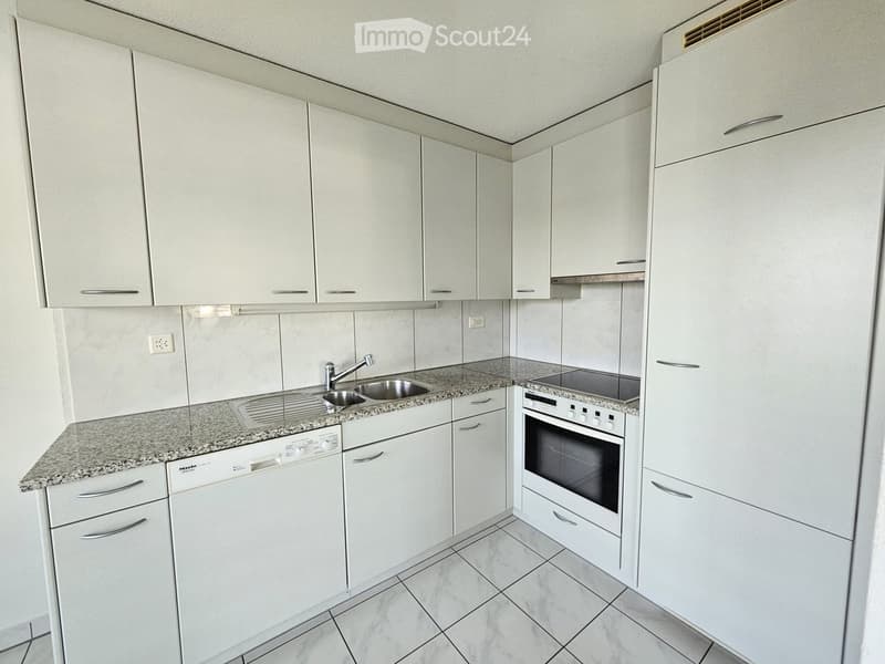 Modern kitchen with white cabinets, granite countertop, stainless steel sink, oven, and dishwasher.