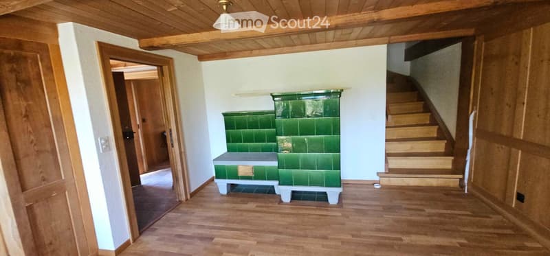 Wooden-floored hallway with a green bench and staircase leading upwards.
