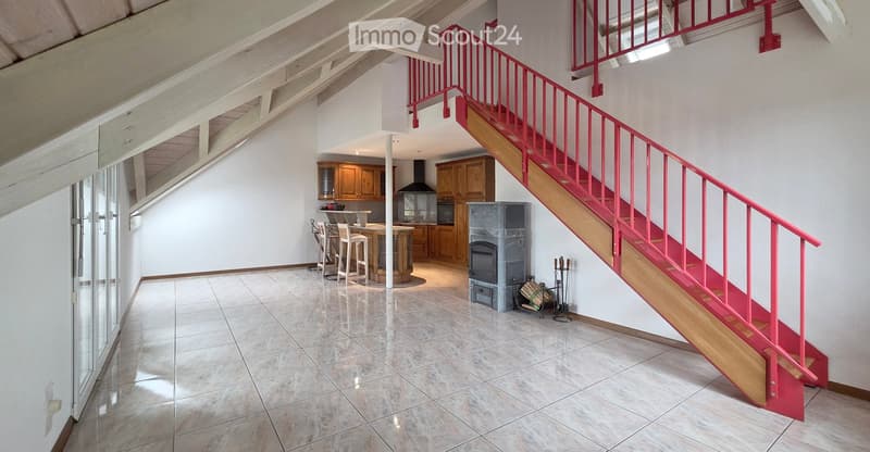 Spacious hallway with a bright red staircase leading to an upper level, featuring wooden steps and railings, a tiled floor, and a view into a kitchen area with wooden cabinets and a central island.